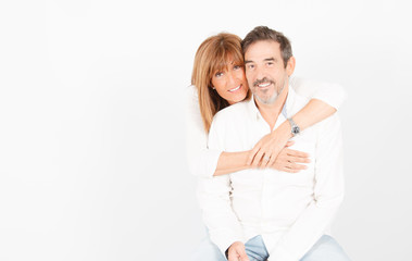 A 50-year-old adult couple poses in a photographic studio in a cheerful way with a white background.