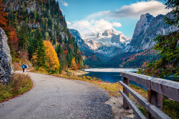Couple walking around a Vorderer/Gosausee lake. Nise autumn scene of Alps with Dachstein glacier on background. Great morning view of Austrian Alps, Upper Austria, Europe.