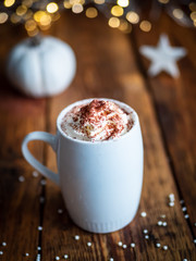 Heiße Schokolade mit Sahne in einer weißen Tasse auf einem braunen Holztisch, Weihnachtsdekoration