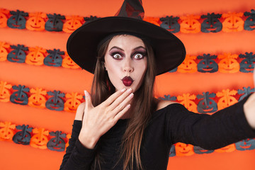 Image of witch girl in halloween costume looking at camera in surprise