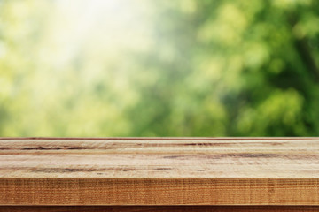 Fototapeta premium Blurred abstract green bokeh of garden and wooden table background.
