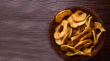 Fototapeta premium Top view of bowl with dried apple chips on wooden table