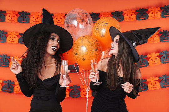 Image of witch women in black halloween costume drinking champagne