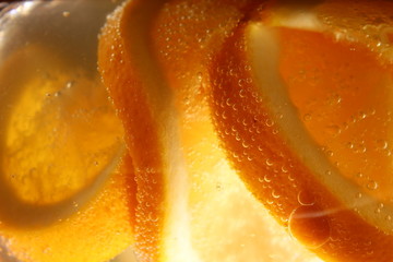Naklejka na ściany i meble orange cut into slices in a glass of sparkling water.