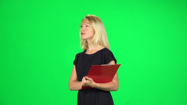 Woman with a red folder goes carefully looking around and taking notes, Chroma Key