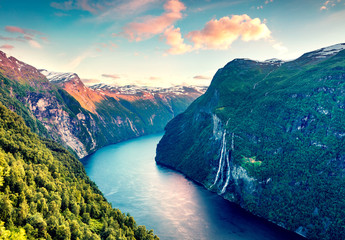 Splendid summer sunset of Sunnylvsfjorden fjord canyon, Geiranger village location, western Norway. Aerial evening view of famous Seven Sisters waterfalls. Beauty of nature concept background. - obrazy, fototapety, plakaty