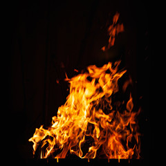 Bright fire flame on a dark background. Fire burning at night. Bonfire in the barbecue, fireplace...