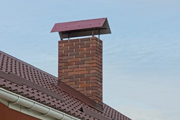 one large brown brown chimney pipe on a tiled roof against a blue sky