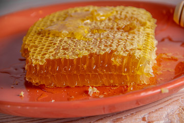 Honeycombs on an orange plate, flowing sticky honey, organic product