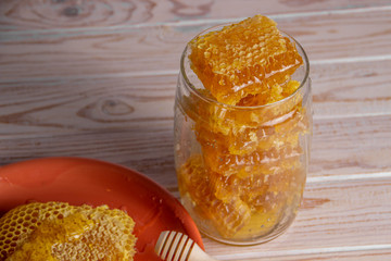 Sweet honeycombs in a glass jar with a wooden spoon for honey