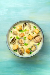 Clam chowder with fresh parsley and croutons, shot from the top on a blue background with a place for text