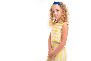 A little girl with red heap hair in a white and yellow striped summer suit, with a blue bandage on...