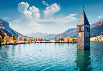 Picturesque autumn view of Tower of sunken church in Resia lake. Wonderful morning scene of Italian Alps, South Tyrol, Italy, Europe. Traveling concept background.