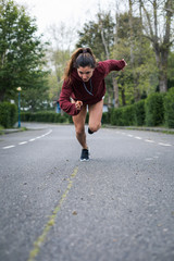 Fast powerful young woman sprinting. Running training on urban suburbs road.