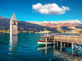 Attractive autumn view of Tower of sunken church in Resia lake. Spectacular morning scene of Italian Alps, South Tyrol, Italy, Europe. Traveling concept background.
