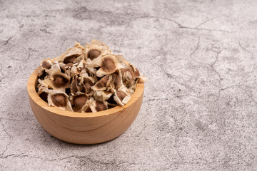 Moringa Oleifera seeds dried in a wooden bowl on the cement floor. Top food for health.