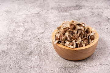 Moringa Oleifera seeds dried in a wooden bowl on the cement floor. Top food for health.
