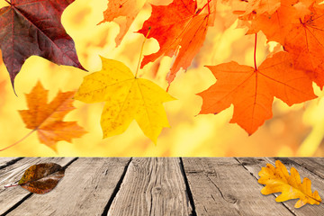 Naklejka na ściany i meble Autumn sunny background. Empty rustic wooden table against colorful maple, oak leaves.