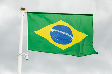 Brazilian flag waving in the wind against white cloudy sky
