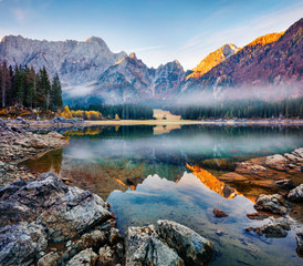 Foggy autumn view of Fusine lake. Picturesque morning scene of Julian Alps with Mangart peak on background, Province of Udine, Italy, Europe. Traveling concept background.
