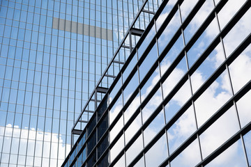 Fototapeta na wymiar Tall glass building of business centre reflecting blue sky