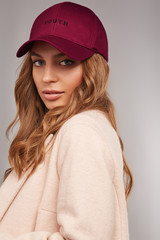 Close-up shot of blonde European lady with wavy hair in a pale pink jacket and a burgundy baseball...