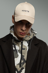 Close-up portrait shot of a short-haired European man dressed in a dazzle hooded top, a black...
