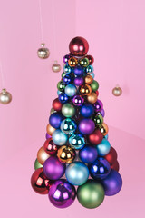Christmas tree made of ball decoration on pink background.