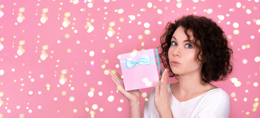 Young beautiful girl with curly hair holding a gift.