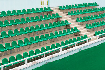 Rows of green spectator seats at sport facility with nobody, diagonal view.