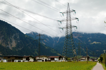 Electricity pylons power lines high voltage towers in norwegian mountains landscape, hazy rainy...