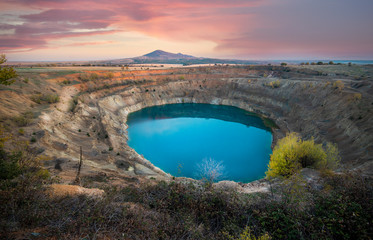 Abandoned ore mining mine with turquoise blue water lake on the outskirts of Tsar Asen, Bulgaria on sunset