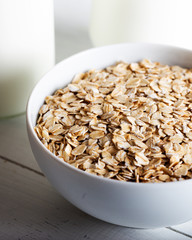 Oatmeal in a bowl with a bottle of milk on wooden background.