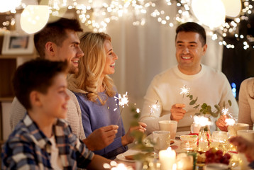 celebration, holidays and people concept - happy family with sparklers having tea party at home