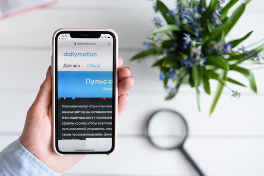 KHARKIV, UKRAINE - April 10, 2019: Apple iPhone X in female hand with dailymotion.com site on the screen.