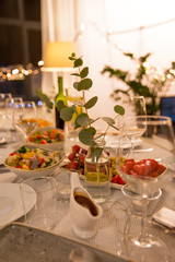 celebration, holidays, catering and eating concept - eucalyptus branch on table served with plates, wine glasses and food for home dinner party