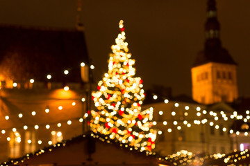 winter holidays and celebration concept - blurred christmas market in evening at town hall square in tallinn, estonia