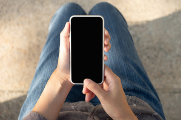 Woman hand holding and using smart phone with blank screen in the park