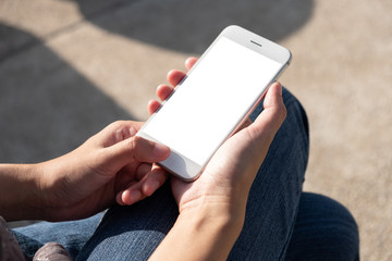 Woman hand holding and using smart phone with blank screen in the park