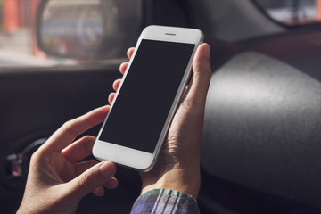 Woman hand holding and using smart phone with blank screen in car