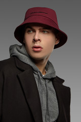 Close-up portrait shot of a short-haired European man dressed in a gray hooded top, a black jacket...