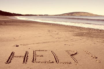 New Zealand help word on beach. Retro filtered colors style. © Tupungato