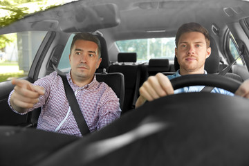 driver courses and people concept - car driving school instructor teaching young man to drive
