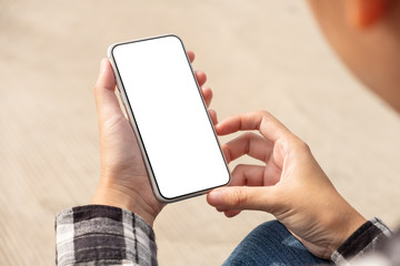 Woman hand holding and using mobile phone with blank screen sitting in the outdoor