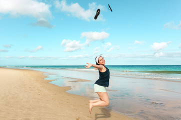 Fototapeta na wymiar Young woman jumping smiling on the beach sand by the sea