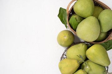 Fresh pomelo, pummelo, grapefruit, shaddock on white cement background in bamboo basket. Autumn seasonal fruit, top view, flat lay, tabletop shot.