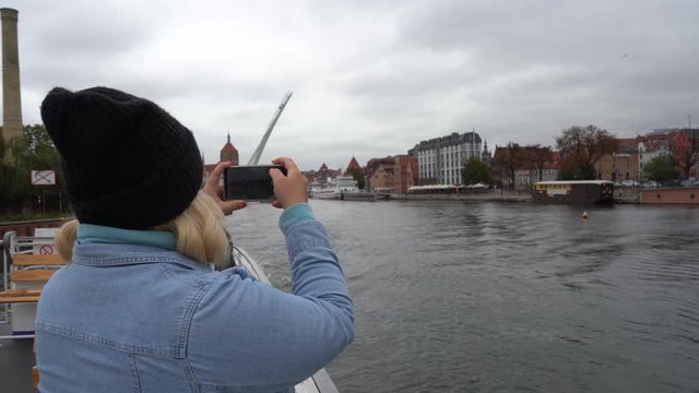 Gdansk, Poland - September 2019: a girl in a hat on a ship takes a photo on a smartphone and crept into the camera lens.