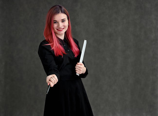 Portrait of a pretty student girl with colored hair in a black suit on a gray background in the studio.