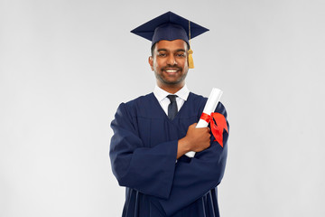 education, graduation and people concept - happy smiling indian male graduate student in mortar...