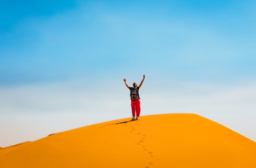 Sporty woman in Merzouga dunes of Sahara desert Morocco Africa. Travel and inspiration concept